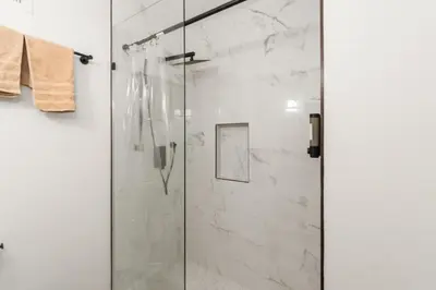 a bathroom with a glass shower with marble walls at Cozy 1BR level apartment w patio & workstation in Jersey City