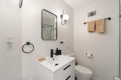 a white bathroom with a sink and a mirror at Holiday Home Brownstone City Stay 5BEDS, Private Dual Units in Jersey City