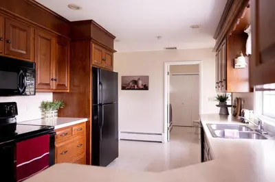 a kitchen with wooden cabinets and a black refrigerator at Cozy Home In The Middle Of Amish Country in Ronks
