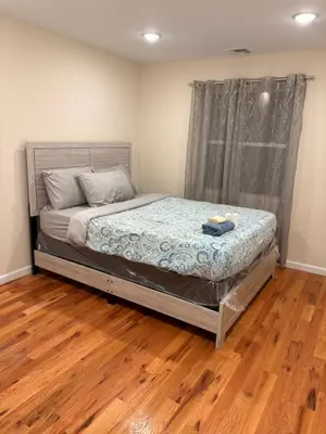 a bedroom with a bed and a wooden floor at Luxury Apartment near Airport in Newark