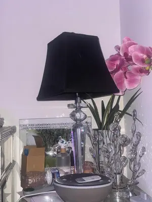 a lamp on a table with a vase and flowers at Luxury Apartment near Airport in Newark