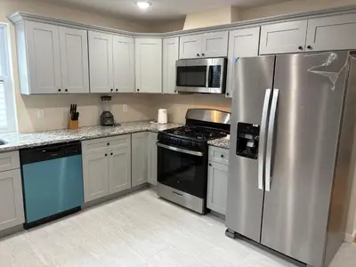 a kitchen with white cabinets and a stainless steel refrigerator at Luxury Apartment near Airport in Newark