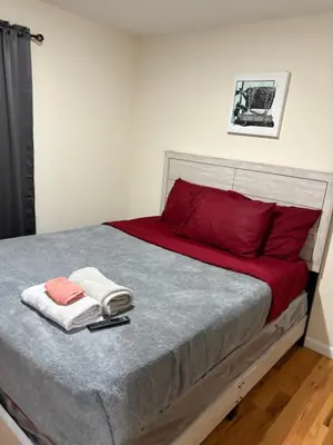 a bed with red pillows and towels on it at Luxury Apartment near Airport in Newark
