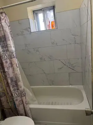 a bathroom with a white tub and a window at 2131 Double Room F in Philadelphia