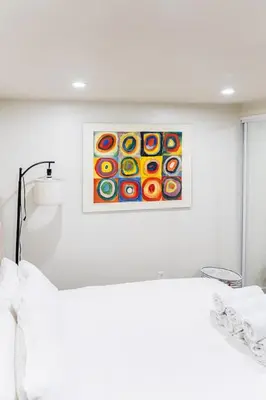 a white bedroom with a painting on the wall at Cozy and Convenient Studio with 3 beds 10 Minutes to NYC in Union City
