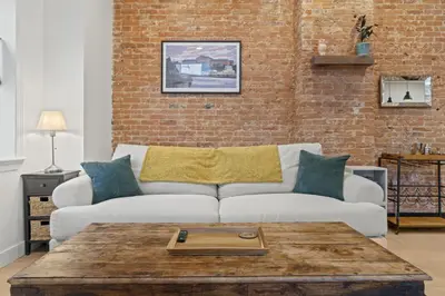 a living room with a couch and a brick wall at City Living without Compromise Full-Size 1BR in Philadelphia