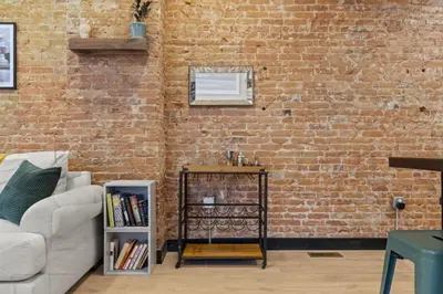 a living room with a brick wall and a table at City Living without Compromise Full-Size 1BR in Philadelphia