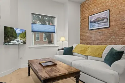 a living room with a couch and a brick wall at City Living without Compromise Full-Size 1BR in Philadelphia