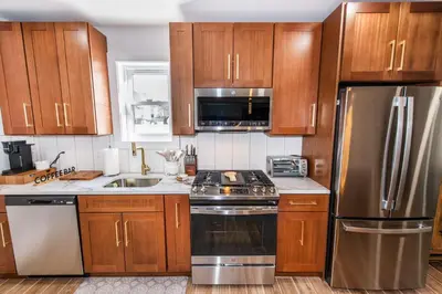 a kitchen with wooden cabinets and stainless steel appliances at Luxury Apartment in Irvington in Irvington