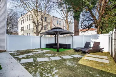 a patio with an umbrella and two chairs and a bench at Luxury Apartment in Irvington in Irvington