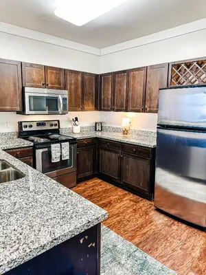 a kitchen with wooden cabinets and a stainless steel refrigerator at The Waverly in Newark