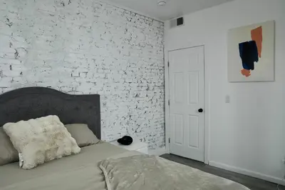 a bedroom with a bed and a white brick wall at Prime Oasis,1 mi to Temple U,Washer and Dryer,Free Snacks in Philadelphia