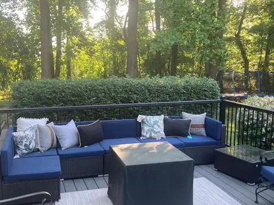 a blue couch with pillows sitting on a deck at Lux Home 5 min to Train and Airport