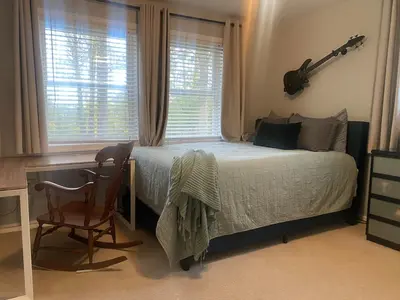 a bedroom with a bed and a desk and a guitar at Lux Home 5 min to Train and Airport