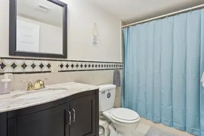 a bathroom with a toilet and a blue shower curtain at Cozy 3 bedroom in Center City Philadelphia in Philadelphia