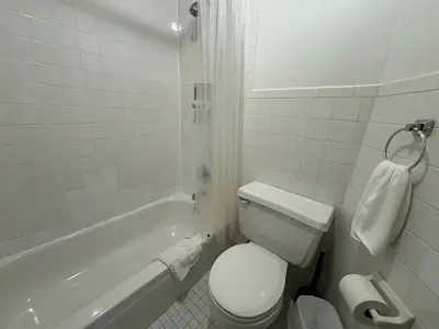 a white bathroom with a toilet and a bath tub at The W50 Metropolitan in New York