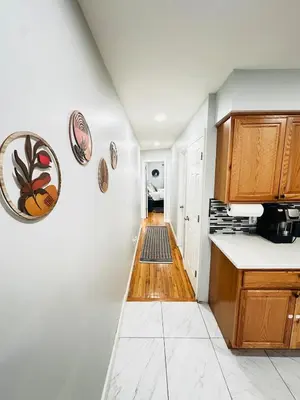 a kitchen with white walls and wooden cabinets at Lux NYC Stay 3Bed2Bath w parking in Jersey City