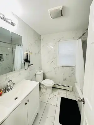 a white bathroom with a toilet and a sink at Lux NYC Stay 3Bed2Bath w parking in Jersey City
