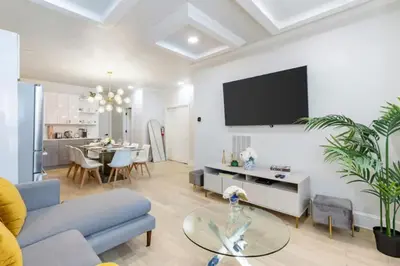 a living room with a couch and a tv on a wall at Chic 3BR-4BD-3Bath Oasis with Backyard Near NYC in Jersey City