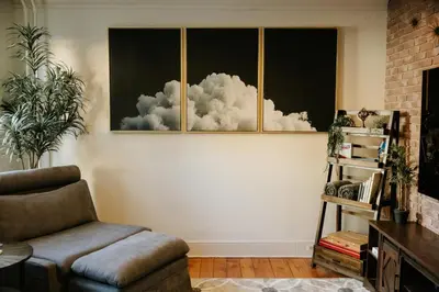 a living room with a chair and a painting of clouds at The Ashfield House - Close to Downtown Lancaster in Lancaster