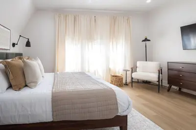 a white bedroom with a bed and a chair at Excellence by Urooms Apartments Near NYC and Newark Airport with Parking in Elizabeth