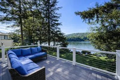 a deck with a couch and a view of a lake at Lakefront House 30 Min to NYC & MetLife Stadium