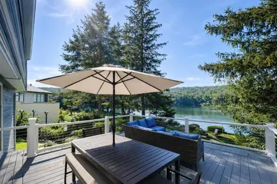a wooden table with an umbrella on a deck at Lakefront House 30 Min to NYC & MetLife Stadium