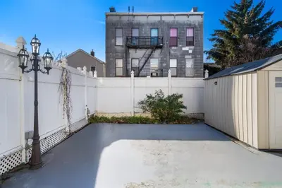 a driveway with a white fence and a building at Queen Bedroom w Ensuite Bathroom - Mins from NYC in Jersey City