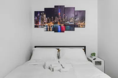 a white bed with a city skyline in the background at Queen Bedroom w Ensuite Bathroom - Mins from NYC in Jersey City