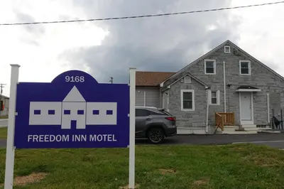 a sign in front of a house with a freedom inn motel at Freedom INN Motel in Grantville