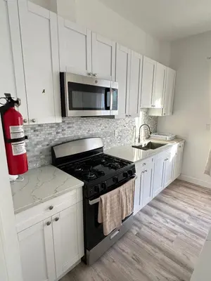 a white kitchen with a stove and a microwave at Beautiful and comfortable room, close to New York Hermosa y cómoda habitación, cerca a New York in West New York