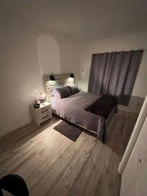 a bedroom with a bed and a night stand with a window at Beautiful and comfortable room, close to New York Hermosa y cómoda habitación, cerca a New York in West New York