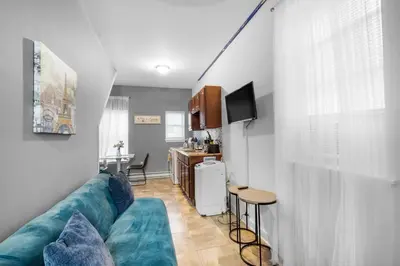 a living room with a blue couch and a kitchen at Modern 2BR 10 Mins to Metro in Philadelphia