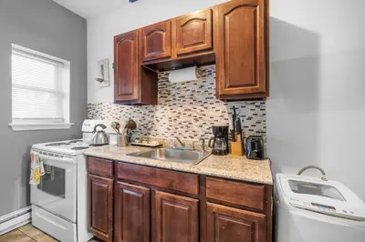 a kitchen with wooden cabinets and a sink at Modern 2BR 10 Mins to Metro in Philadelphia