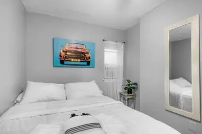 a bedroom with a bed with a picture of a car on the wall at Modern 2BR 10 Mins to Metro in Philadelphia