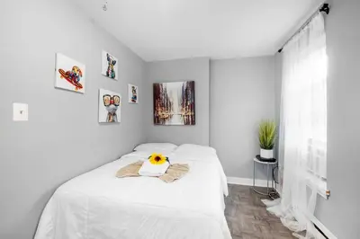 a white bedroom with a bed with a sunflower on it at Modern 2BR 10 Mins to Metro in Philadelphia