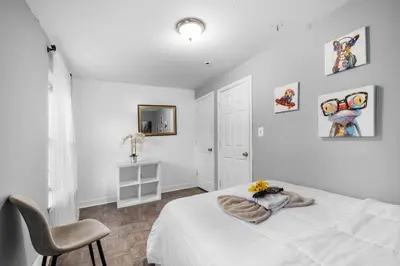a white bedroom with a bed and a chair at Modern 2BR 10 Mins to Metro in Philadelphia