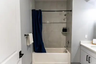 a bathroom with a shower with a blue shower curtain at City Life-2 Bedrooms-Free Indoor Parking-20minNYC in West New York