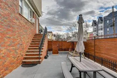 a patio with an umbrella and a bench and stairs at Walk to Public Transit Apt Next to Lincoln Park in Jersey City