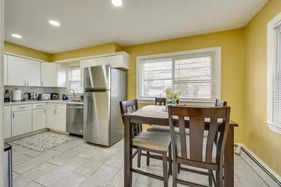a kitchen with a table and a stainless steel refrigerator at Walkable Jersey City Stay Near Parks and Dining! in Jersey City