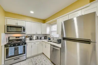 a kitchen with white cabinets and a stainless steel refrigerator at Walkable Jersey City Stay Near Parks and Dining! in Jersey City