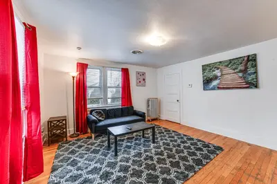 a living room with a black couch and red curtains at Work and Study Binghamton Apt 2 Mi to Downtown in Binghamton
