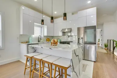 a kitchen with white cabinets and bar stools at 5 Mi to NYC Bright and Chic Jersey City Getaway! in Jersey City