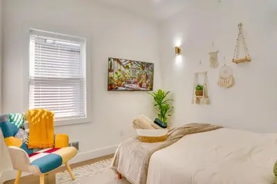 a bedroom with a bed and a chair and a window at 5 Mi to NYC Bright and Chic Jersey City Getaway! in Jersey City
