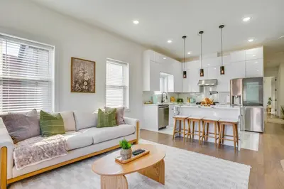 a living room with a couch and a kitchen at 5 Mi to NYC Bright and Chic Jersey City Getaway! in Jersey City