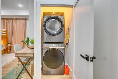 a washer and dryer in a room with a table at 5 Mi to NYC Bright and Chic Jersey City Getaway! in Jersey City