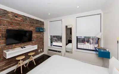 a bedroom with a brick wall and a bed and a tv at East Village by Vibe I in New York