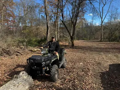 a man sitting on a quad bike in the woods at Live The Outdoors