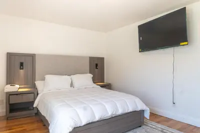 a bedroom with a white bed with a flat screen tv at Spacious 3BR Home Near Newark Airport in Newark