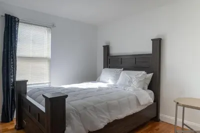a bedroom with a bed with white sheets and a window at Spacious 3BR Home Near Newark Airport in Newark
